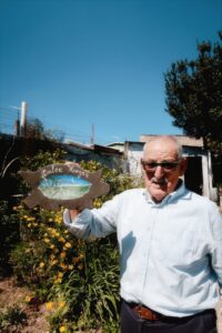 senior man holding dulce hogar sign in garden